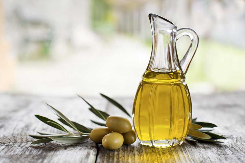 A bottle of olive oil and olives around