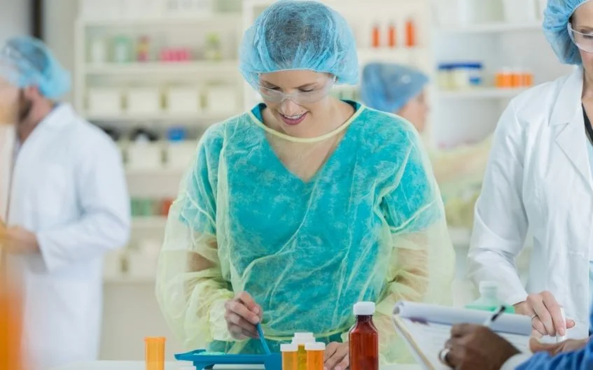 Confident mid adult female pharmacist uses a pill counter to count out patient's prescription...