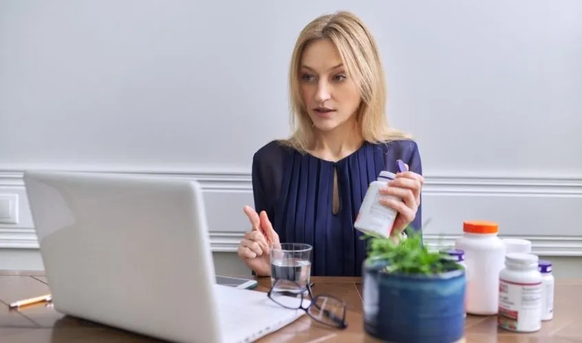 Professional female sitting at table looking at laptop screen