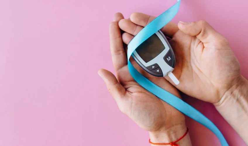 A Person Holding a Blood Glucose Meter and Blue Ribbon Tape